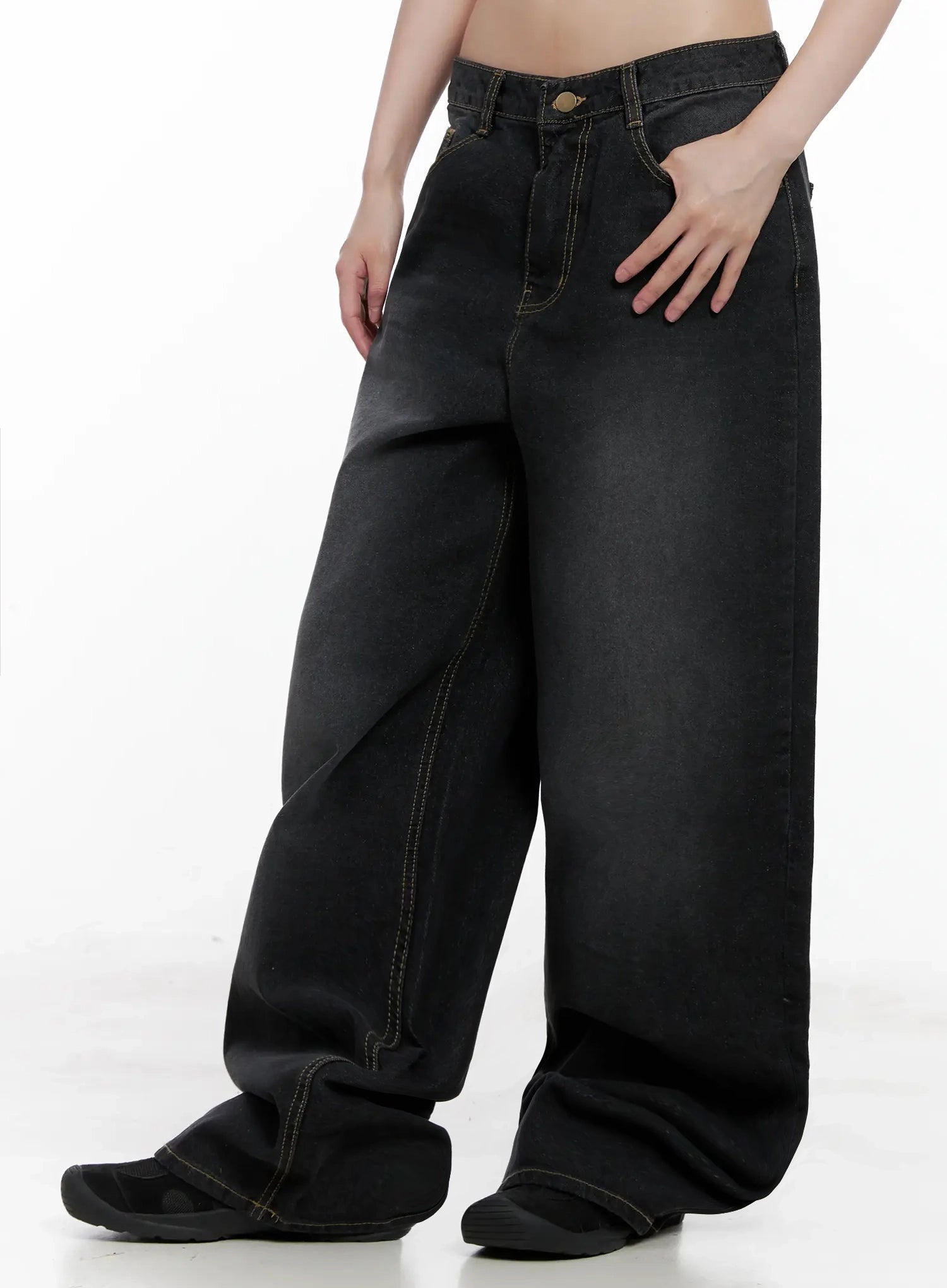 IU Vintage Black Baggy Jeans IL528 in black, side close-up on model, hand on hip showing washed gradient denim texture, contrast topstitching, ultra-wide leg silhouette.