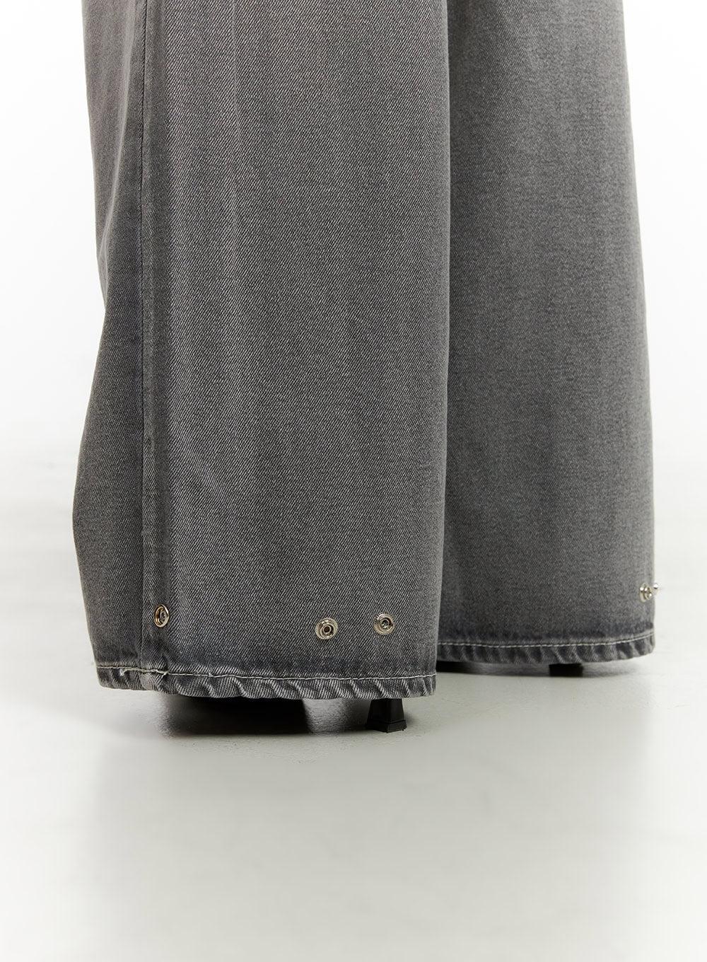 Low Rise Baggy Jeans CY431 in gray, macro detail close-up of hem showing metal eyelet rivets and raw-edge finish on wide-leg washed denim.