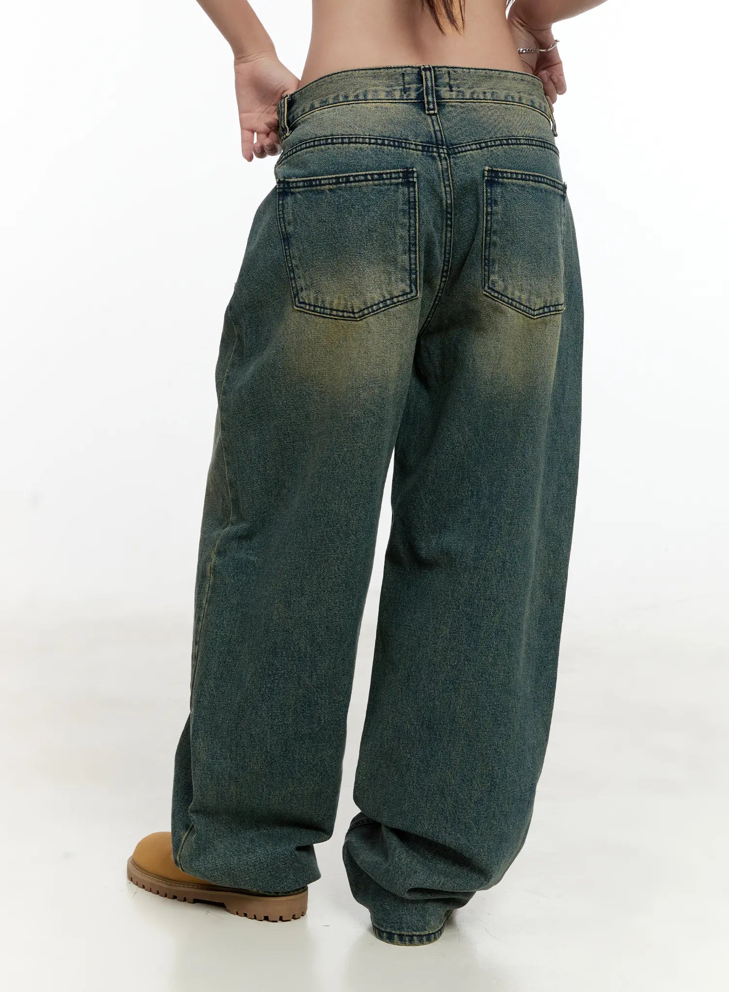 Sooyoung Baggy Vintage Wash Jeans CL531 in dark blue, back close-up on model, showing dual back pockets with topstitching, yellow-tinted vintage wash, and wide-leg hem pooling at boots.