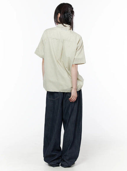 Rowen Baggy Jeans CU519 in dark blue, back full-body on model, flap pockets and contrast stitching visible, paired with striped short-sleeve shirt, model facing away with hair clip detail.