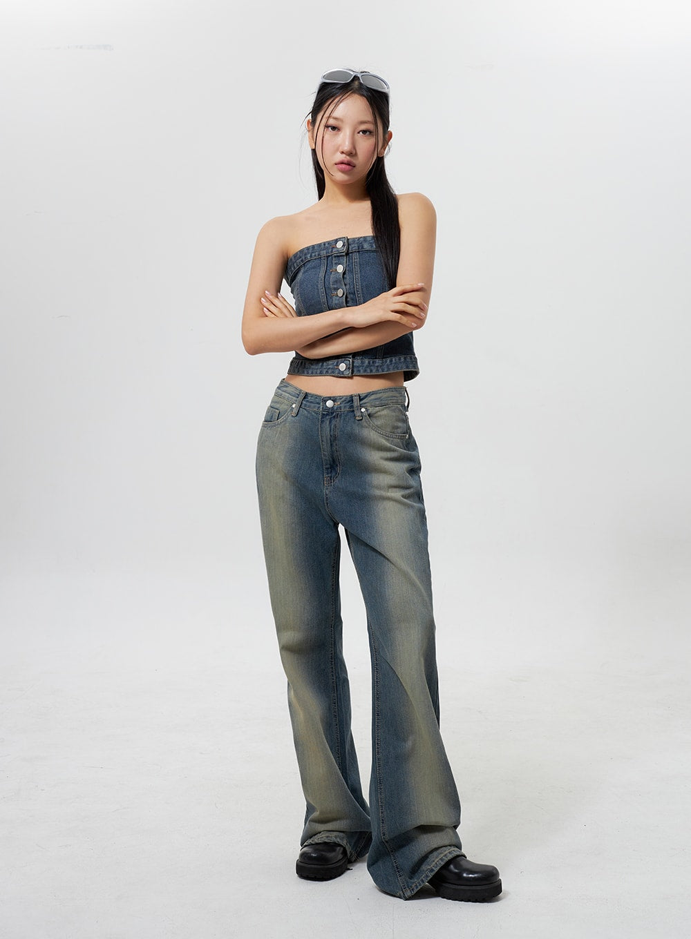 Low Rise Wide Leg Jeans CY323 in vintage blue, full front view on model with arms crossed, low-rise wide-leg denim with yellow-tinted vintage fade wash, paired with denim strapless top and chunky black boots.
