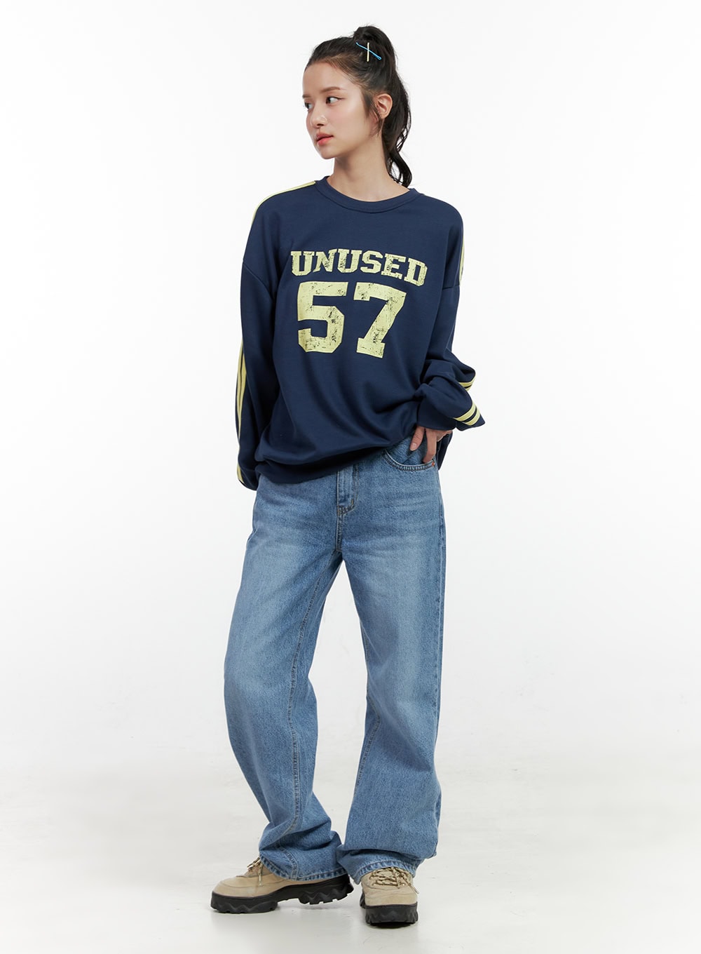 Carly Cloud Wide-Leg Jeans ON404 in blue, three-quarter front on model looking aside, wide-leg washed denim with low-rise waist and flared hem, paired with oversized navy sweatshirt and sneakers.