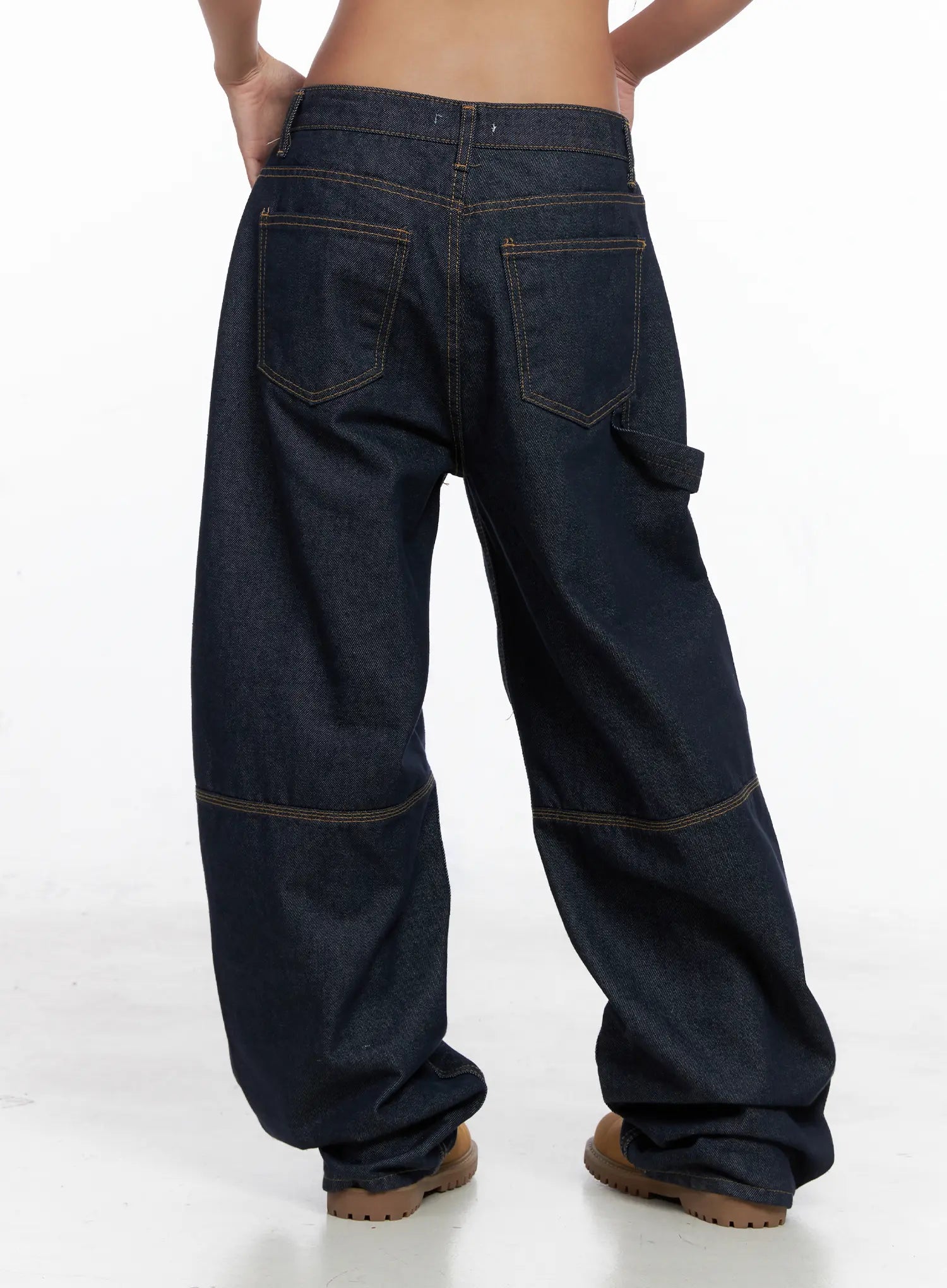 Relaxed Fit Dark Denim Jeans CS522 in dark blue, full back view on model, wide-leg baggy silhouette, dual back pockets, carpenter loop, contrast gold stitching, stacked hem at tan boots.