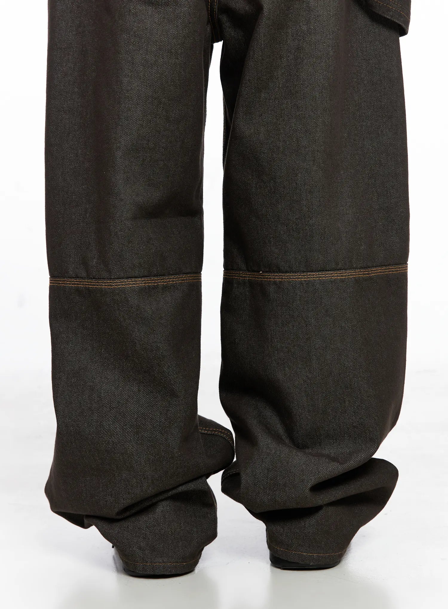 Oaklyn Non-Fade Wide-Leg Jeans CO513 in dark brown, close-up of lower leg detail, horizontal panel seam with orange contrast stitching, raw cotton denim texture, excess fabric pooling at floor.