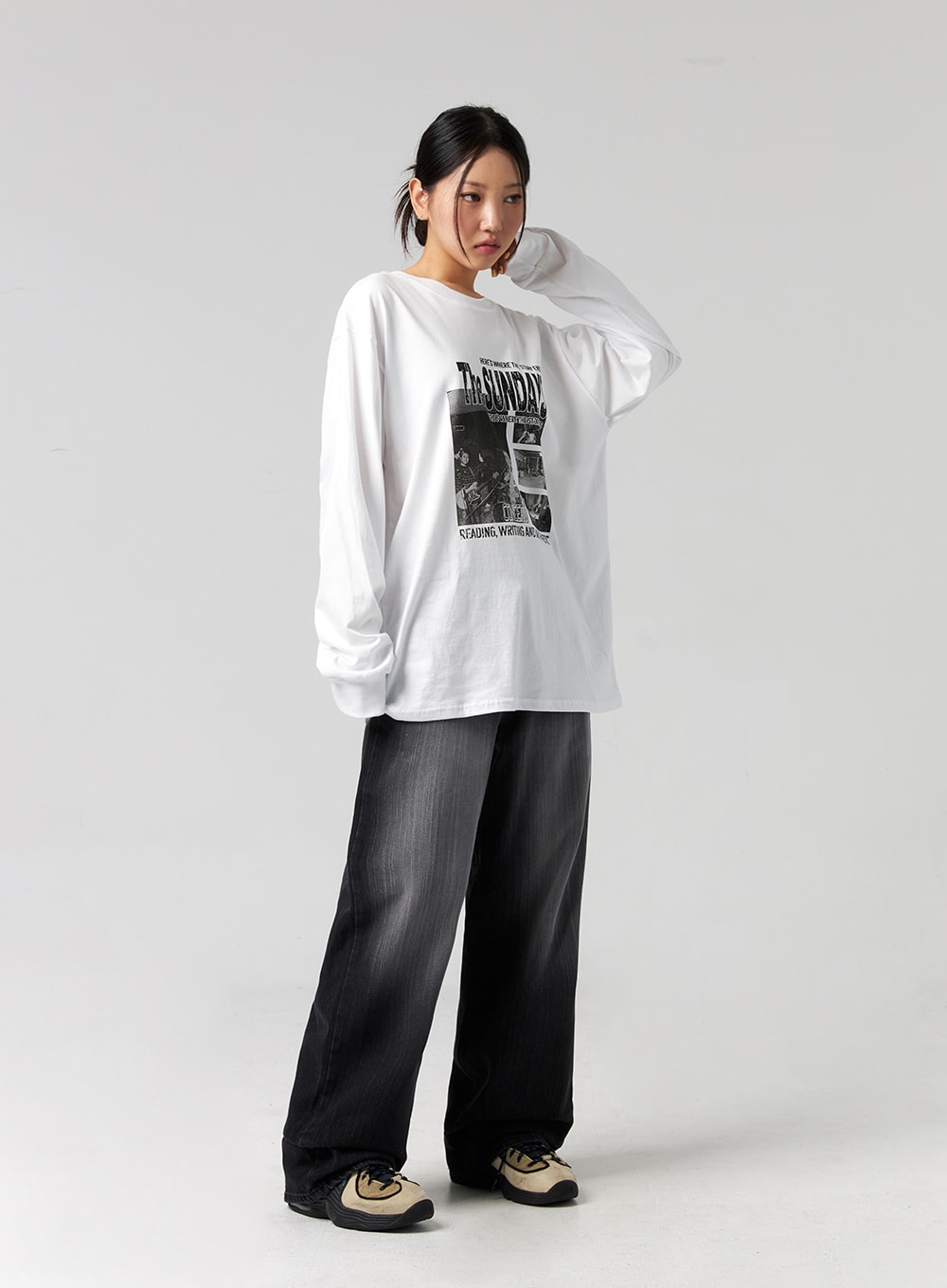 Washed Wide-Leg Jeans CG327 in black, full-body three-quarter shot on model with hand raised to neck, wide-leg washed denim, relaxed silhouette, styled with oversized graphic long-sleeve tee and sneakers.