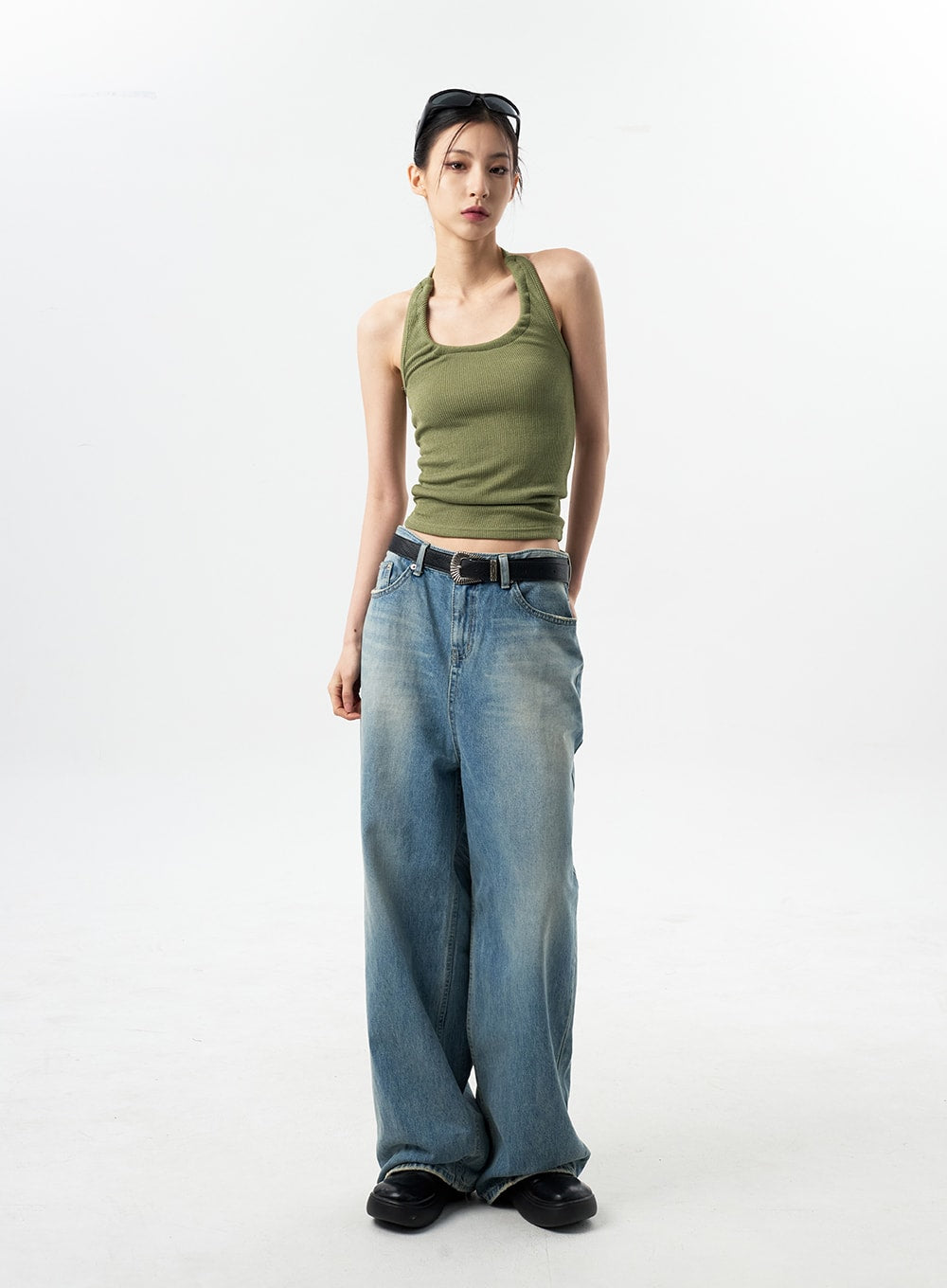 Oversized Jeans Unisex CY312 in washed blue, full-length front view on model standing straight, wide-leg vintage-wash denim, styled with green halter crop top and black belt.