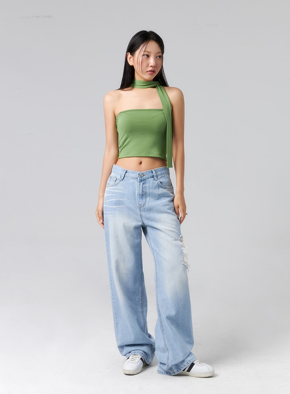 Ripped Side Jeans CL320 in light blue, full-body front view on model arms relaxed, wide-leg washed denim with side rip and frayed destroyed detailing, paired with green halter crop top.