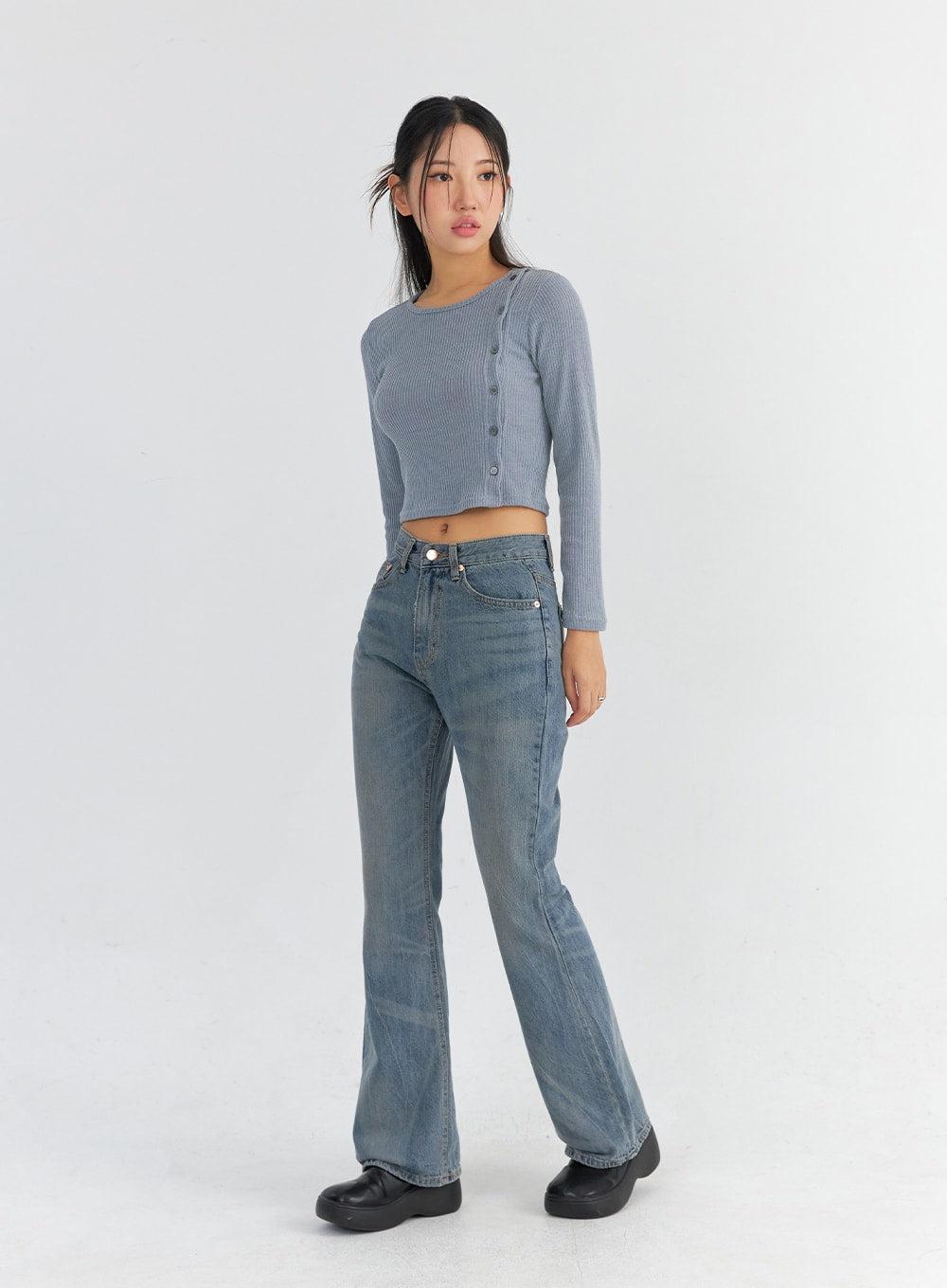 Vintage Washed Bootcut Jeans CO325 in blue, full-body diagonal-front shot on model, slim fit vintage-washed denim showcasing bootcut leg line and high-rise fit, paired with grey ribbed crop top.
