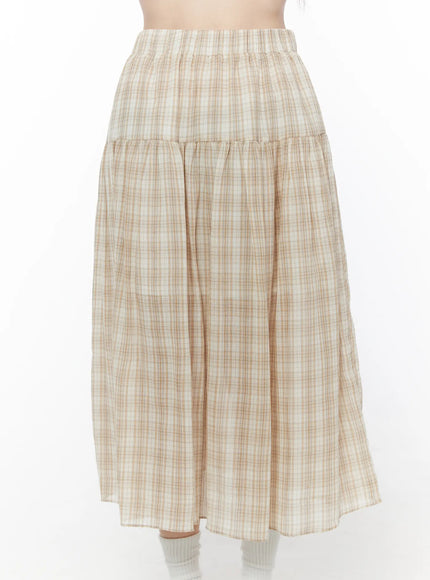Plaid Flare Maxi Skirt CU519 in beige, front product-focused shot cropped at waist on model, highlighting elastic waistband, tiered gather seam, and lightweight plaid woven fabric drape.