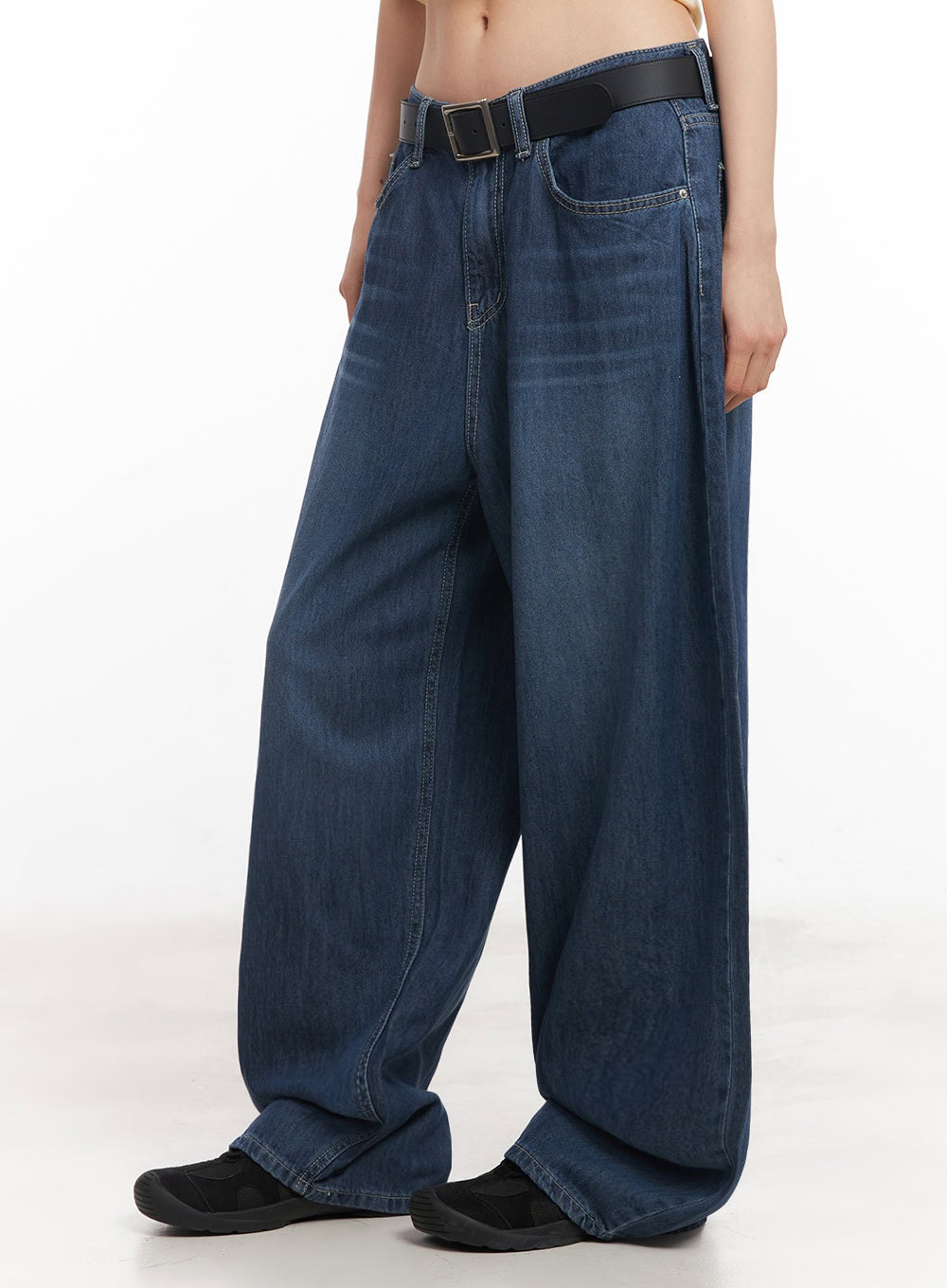 Martha Baggy Jeans IY529 in dark blue, side view on model, showing voluminous wide-leg washed denim drape from hip to hem, worn with black belt and black sneakers.