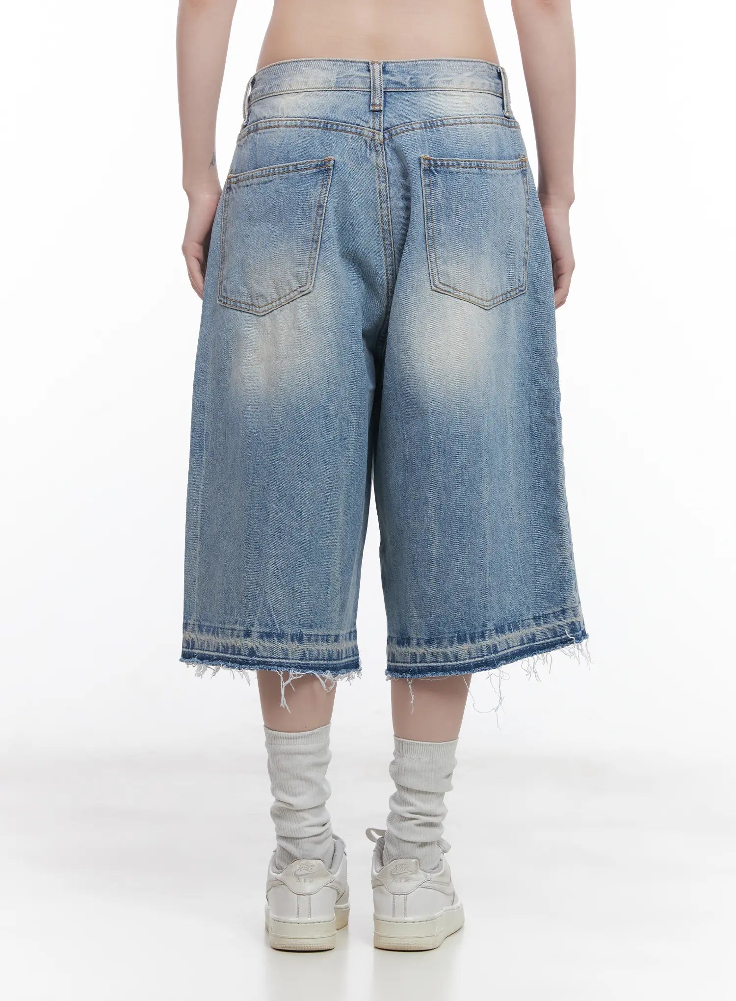 Light Wash Vintage Jorts CU519 in blue, back waist-to-ankle close-up on model, back pockets with washed fading detail, low waist and raw frayed hem, wide-leg midi cut, grey socks.