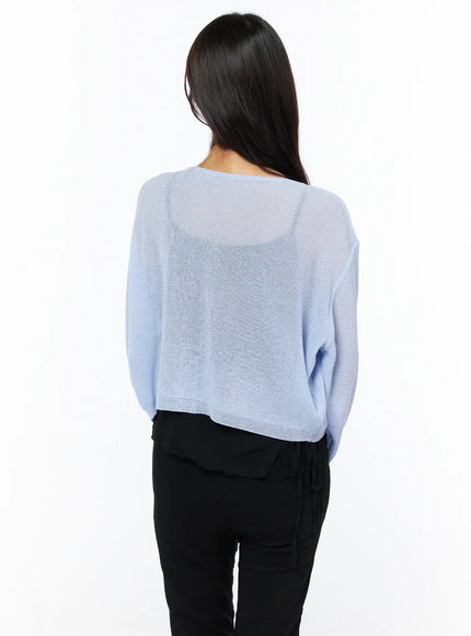Sheer V-Neck Cardigan CU522 in light blue, back view on model, semi-sheer open knit revealing slight transparency, cropped length, paired with black tie-waist pants.