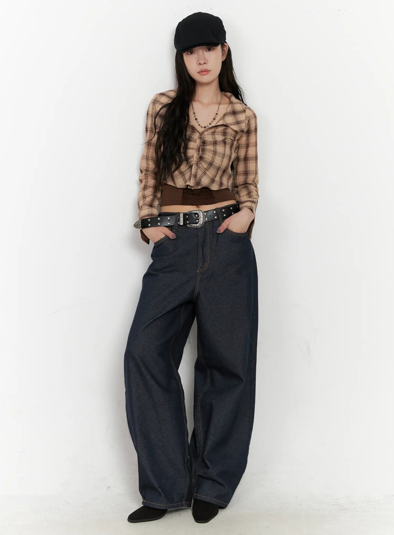 Heaven Wide-Leg Dark Washed Jeans CN513 in dark blue, front full-length editorial shot on model leaning against wall, hands in pockets, styled with plaid shirt, cap, and western belt.