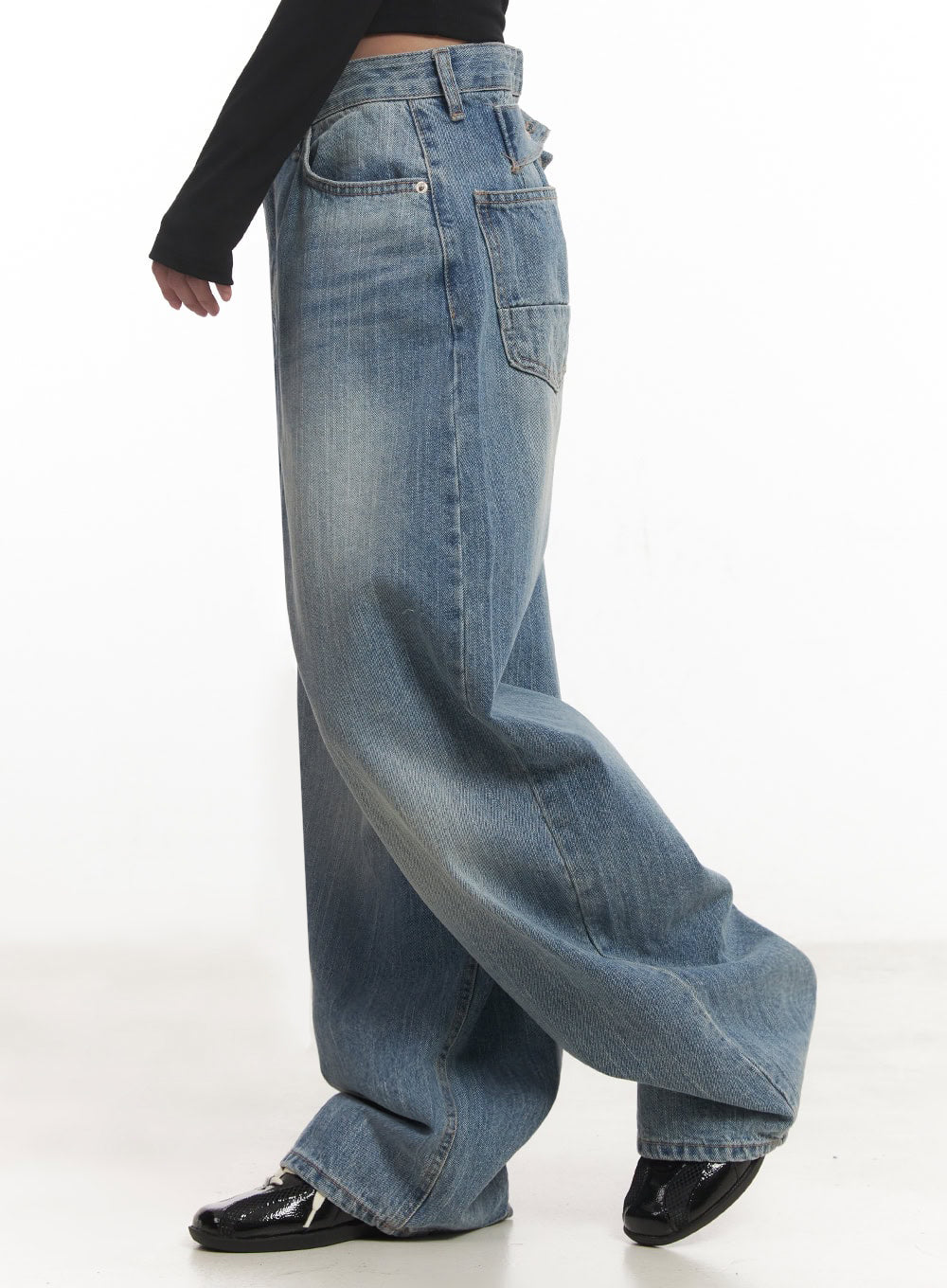 Yvette Washed Baggy Jeans IA517 in light blue, side close-up from hip to hem on model, wide-leg washed denim with patch side pocket and faded finish clearly visible, styled with black long-sleeve top.