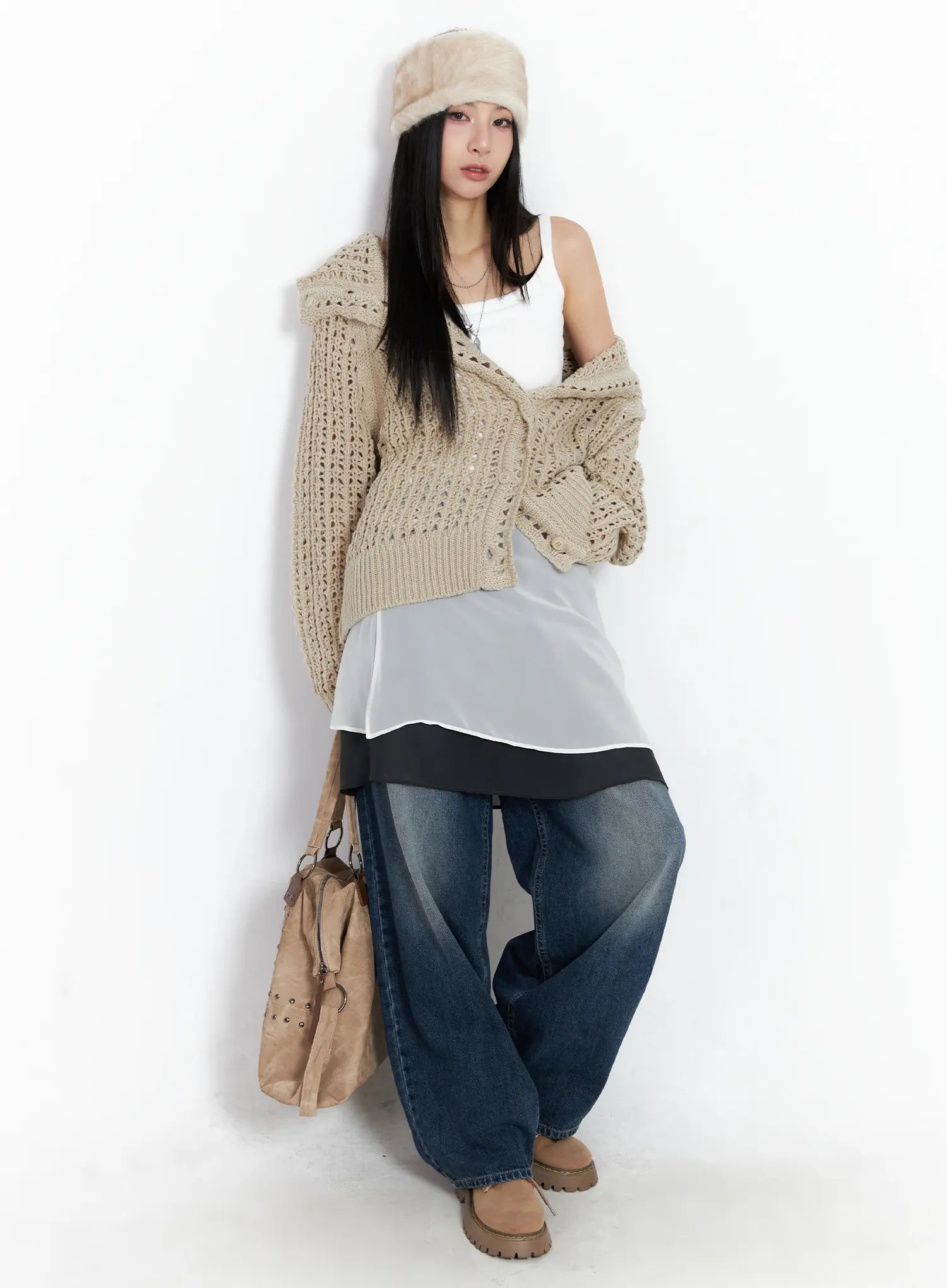 Aisha Washed Baggy Jeans CC1109 in mid blue, full-length lifestyle shot on model leaning against wall, baggy wide-fit denim styled with crochet cardigan, layered top, fur hat, and suede tote.