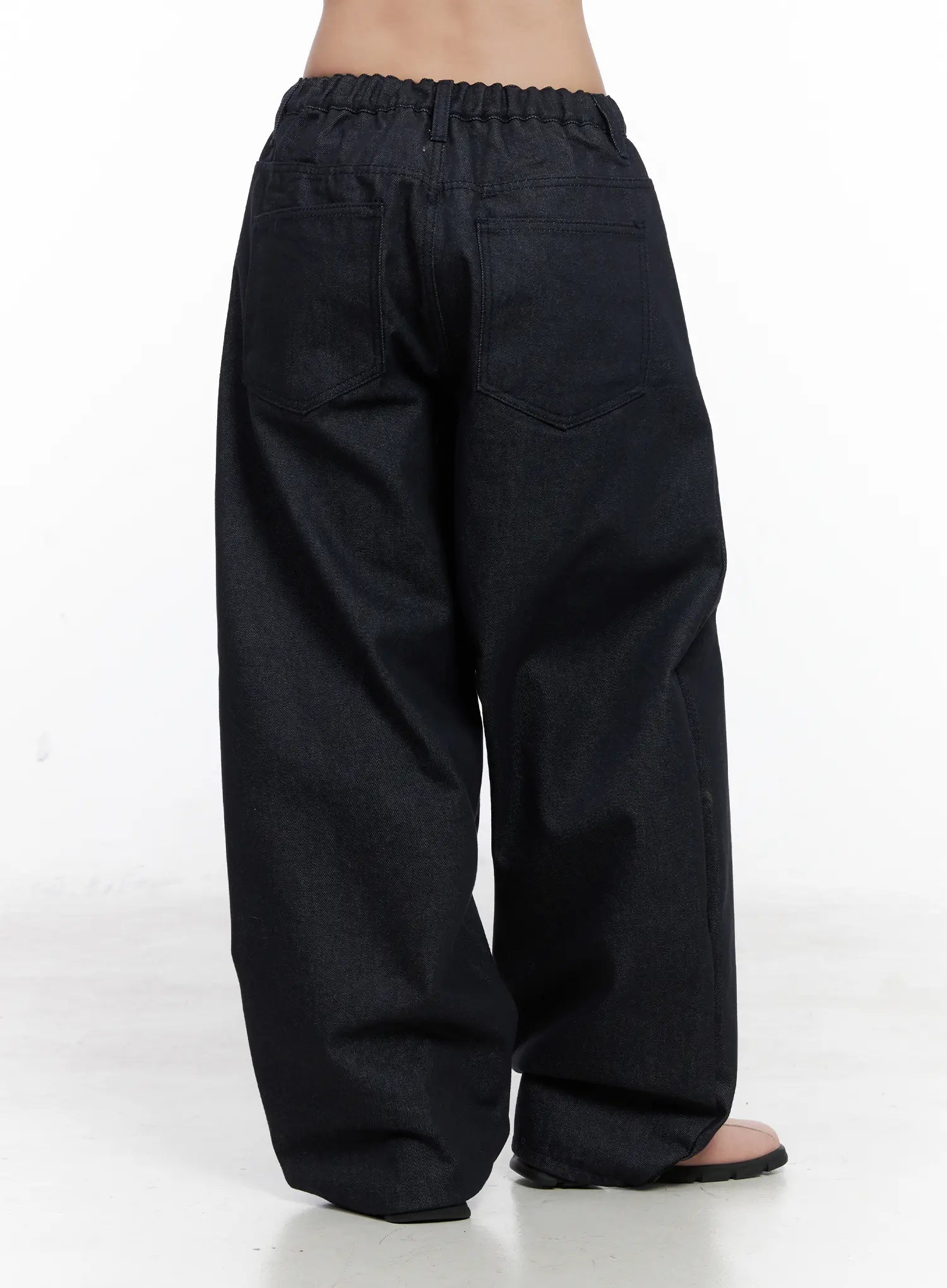 Solana Unwashed Wide-Leg Jeans CN514 in dark indigo, back three-quarter view on model, elastic ruched waistband, wide ballooned leg tapering to hem, back pocket stitching visible.