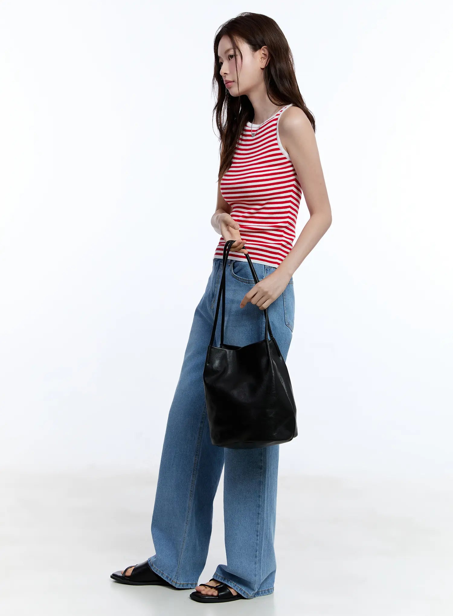 Jisoo Straight-Fit Jeans CU513 in blue, side full-body shot on model looking down, wide-fit washed denim paired with red striped tank and black bucket bag, black sandals.