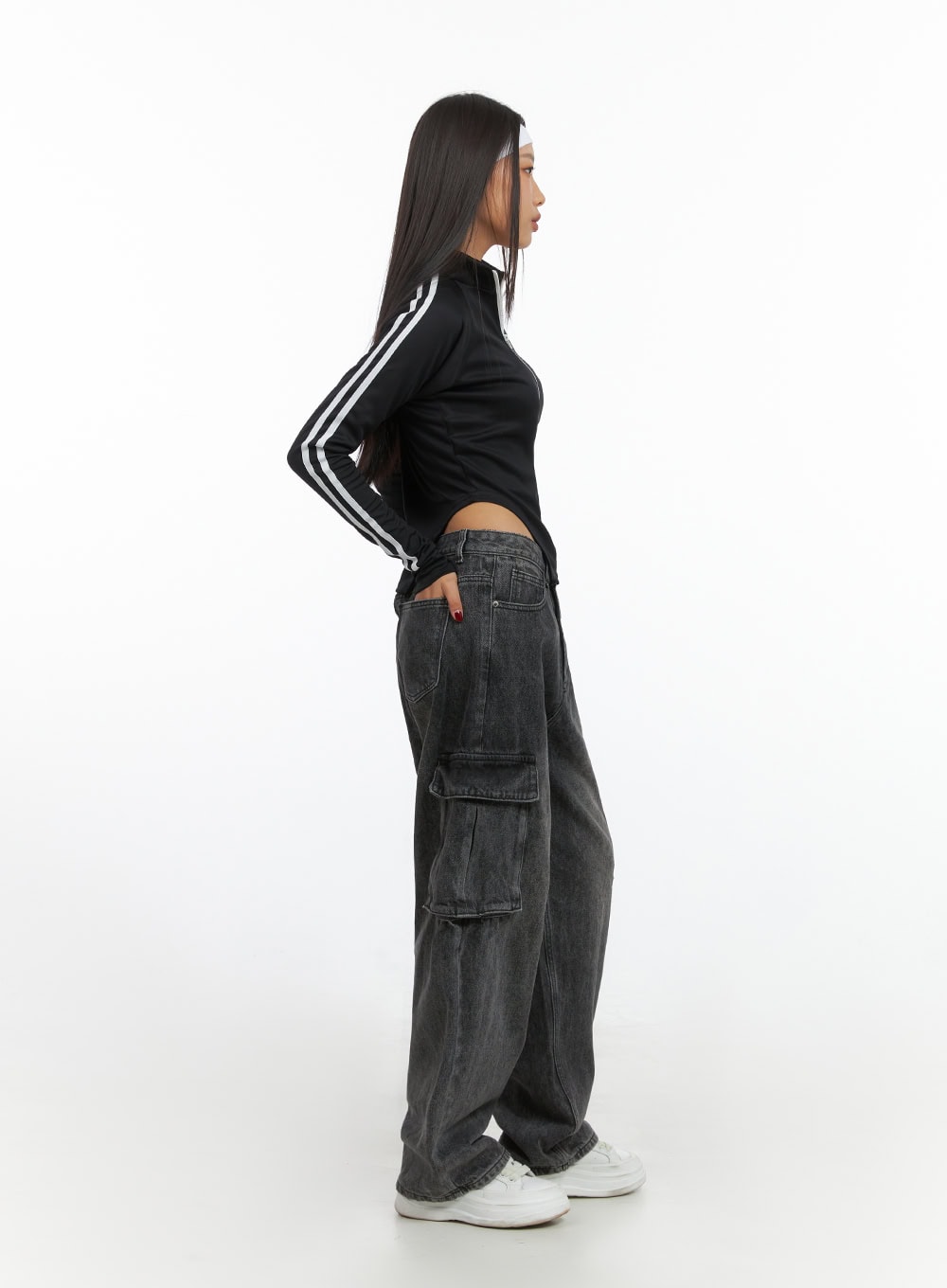Neve Washed Cargo Denim Jeans IS427 in washed black, side profile full-length shot on model, showing wide-leg silhouette and side cargo pocket depth, paired with black crop top and white sneakers.