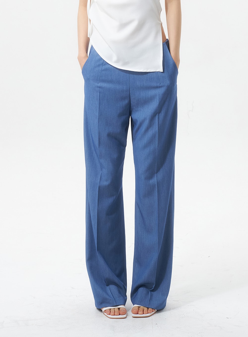 Low Rise Tailored Pants IU326 in blue, front crop shot from waist to ankle on model, low-rise waistband with side pockets and sharp front crease, hands in pockets.