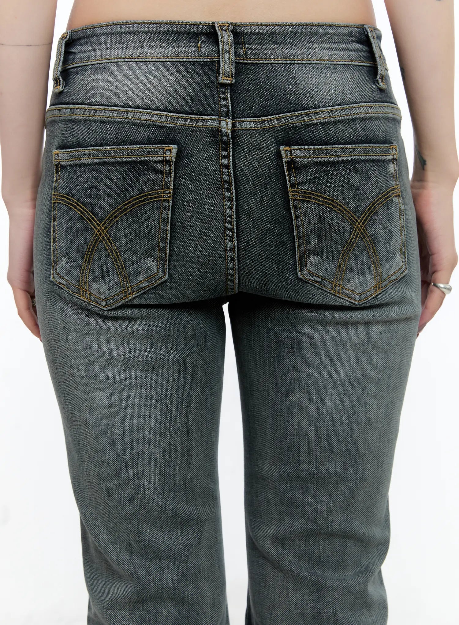 Judith Washed Bootcut Jeans CN517 in blue, close-up back detail on model, arc-stitched dual back pockets with contrast gold topstitching, washed grey cotton-spandex denim texture.