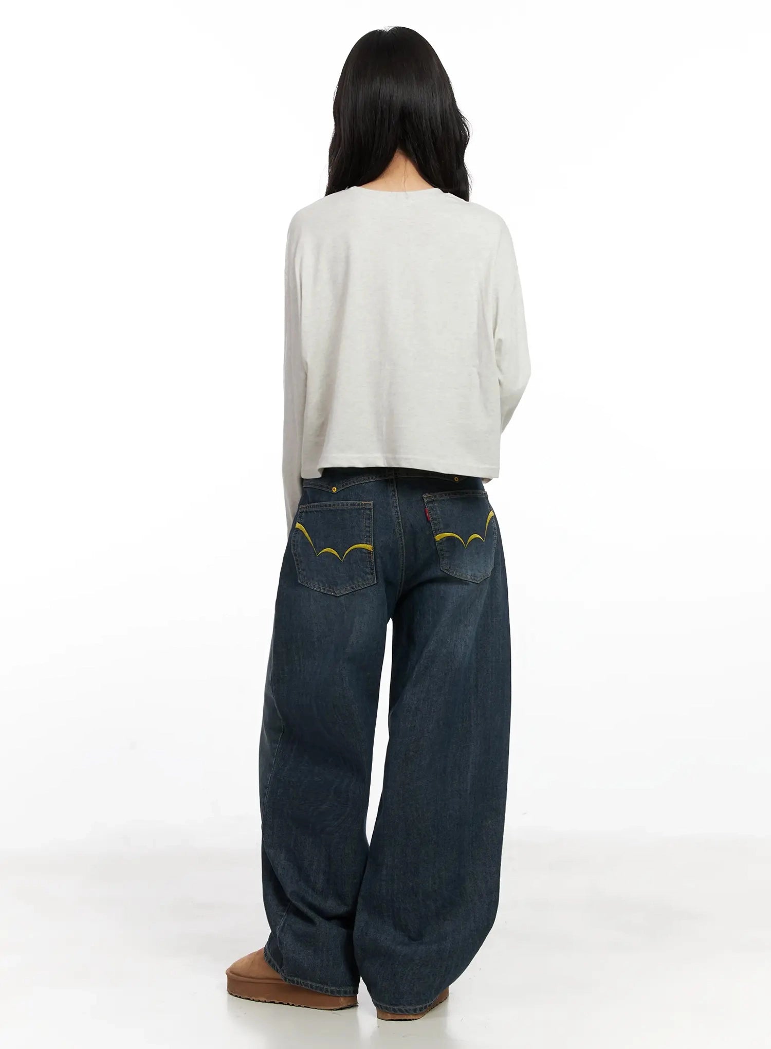 Regina Contrast Stitch Baggy Jeans IN528 in dark blue wash, full back view on model, yellow contrast embroidery stitching on back pockets, wide-leg washed denim with tan UGG boots.