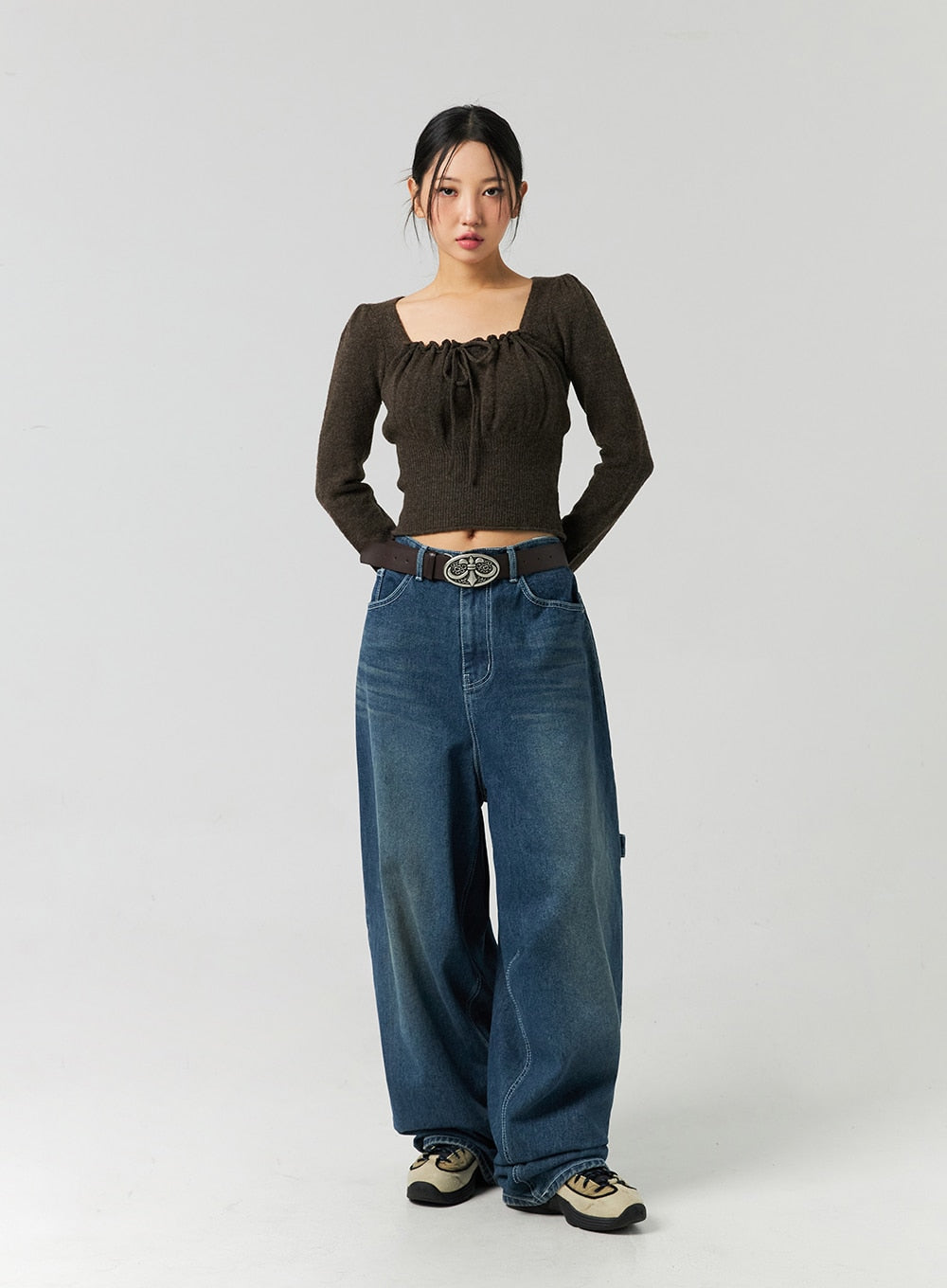 Washed Cotton Wide Leg Jeans CO323 in blue, full-body front on model in neutral stance, wide leg washed denim with high-rise waist and ornate buckle belt, paired with brown square-neck knit top.