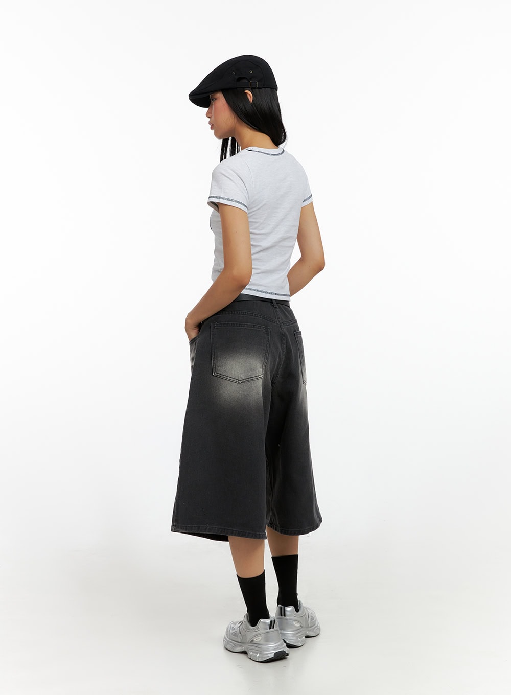Washed Baggy Jorts IL419 in black, back full-body on model, wide-leg midi denim with faded wash, back patch pockets, flared silhouette, paired with white crop tee and silver sneakers.