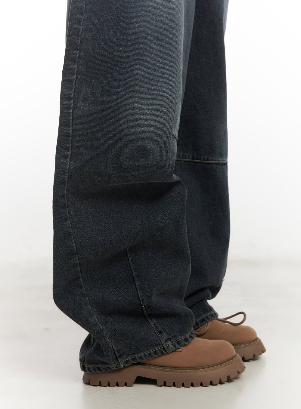 Giselle Stitched Balloon-Fit Jeans CF526 in dark blue, lower-leg detail shot showing horizontal panel stitch seam, extreme wide hem, and washed dark denim texture over brown lug-sole boots.
