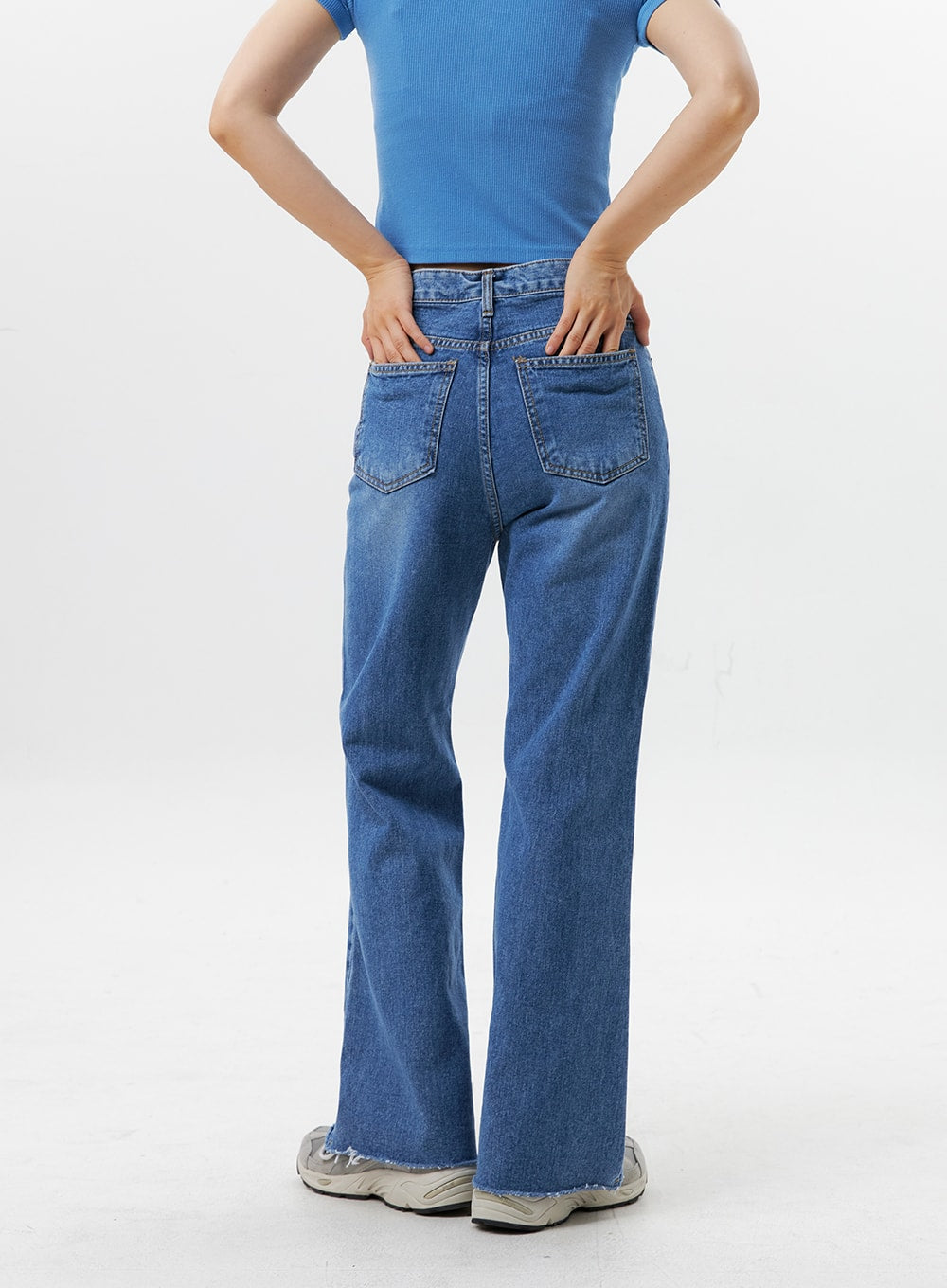 Straight-Leg Jeans OG318 in medium blue, back waist-to-hem close-up on model, two back patch pockets with stitching detail, high-rise waistband, straight cotton denim, raw hem at ankle.