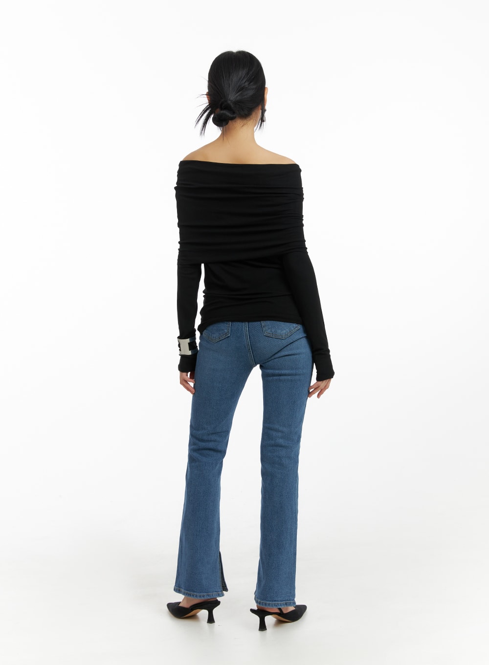 Vintage Flared Jeans IM414 in blue, back full-body on model, showing flared hem slit and five-pocket construction, paired with black off-shoulder top and slingback heels.
