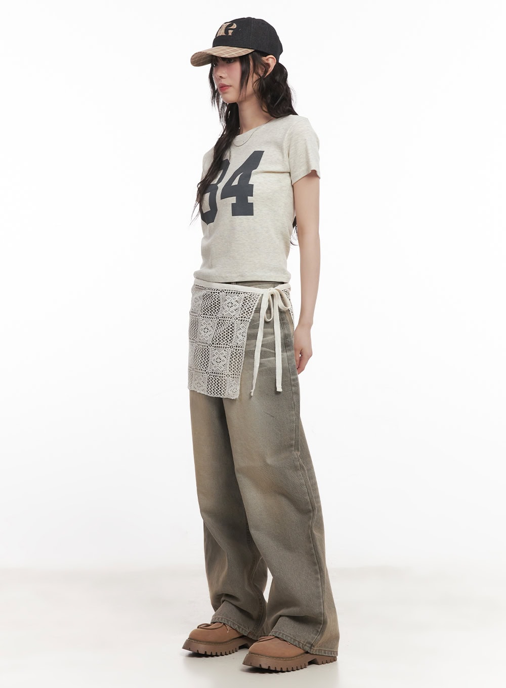 Joey Washed Wide-Leg Jeans CM528 in gray, three-quarter side full-body shot on model looking down, layered with crochet wrap skirt over jeans, cropped graphic tee, baseball cap, and tan lug-sole boots.