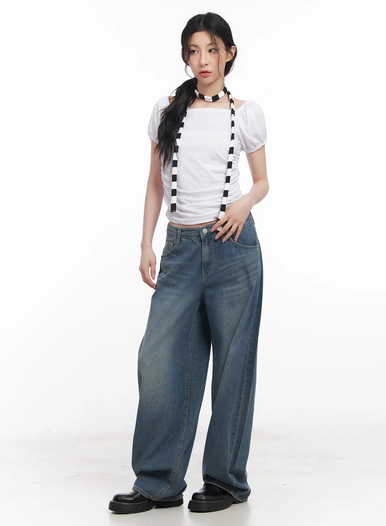 Chaewon Washed Wide-Leg Jeans CU511 in blue, full-body front on model standing straight, low-rise fit with washed finish, styled with white crop top and striped suspender, black loafers.
