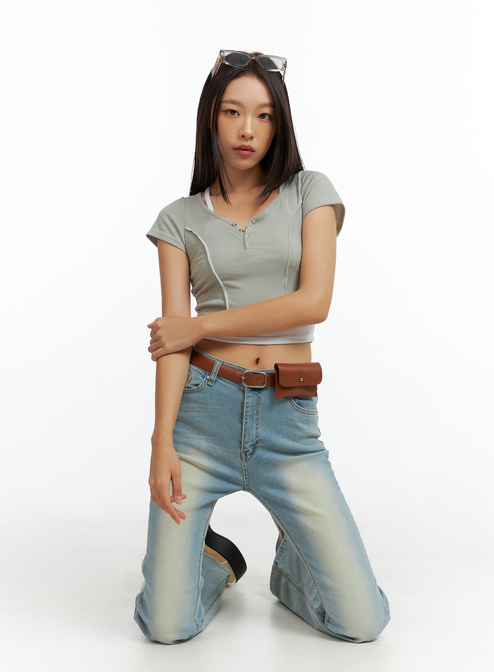 Light Washed Slim Fit Bootcut Jeans IL409 in light blue, editorial kneeling pose on model, washed denim fading visible on thighs, high-rise waist with brown belt bag styling.