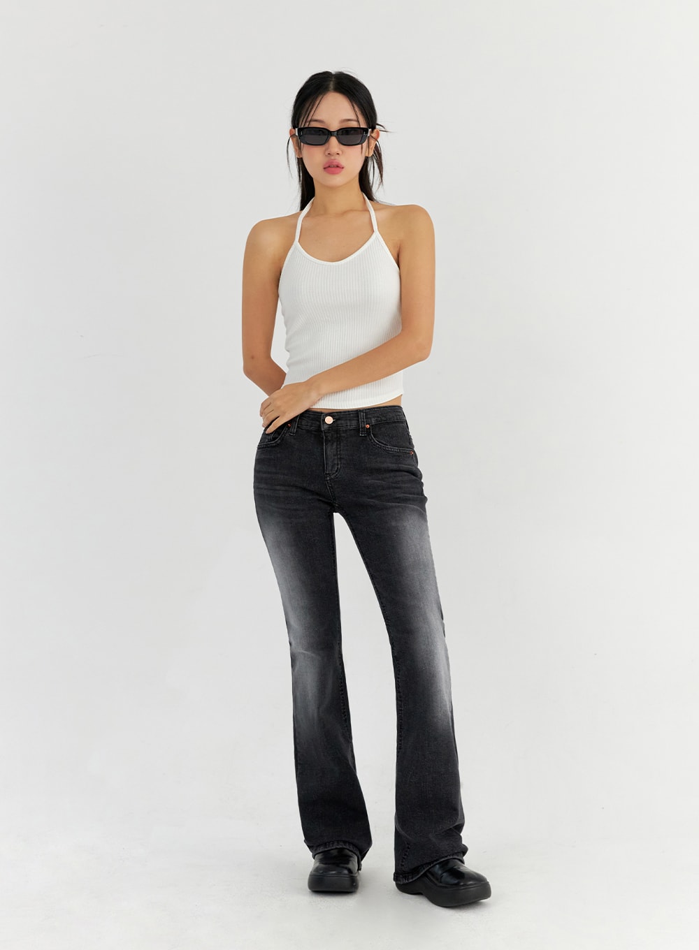 Bootcut Washed Jeans CO325 in dark gray, full-body front view on model wearing sunglasses, slim bootcut washed denim, low-rise, paired with white halter top, hands tucked in pockets.