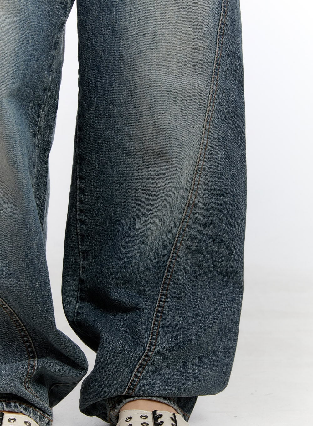 Lucia Stitched Denim Baggy Jeans CO418 in blue, lower-leg detail close-up, showcasing curved outseam stitch, washed denim texture, and oversized hem pooling over shoes.