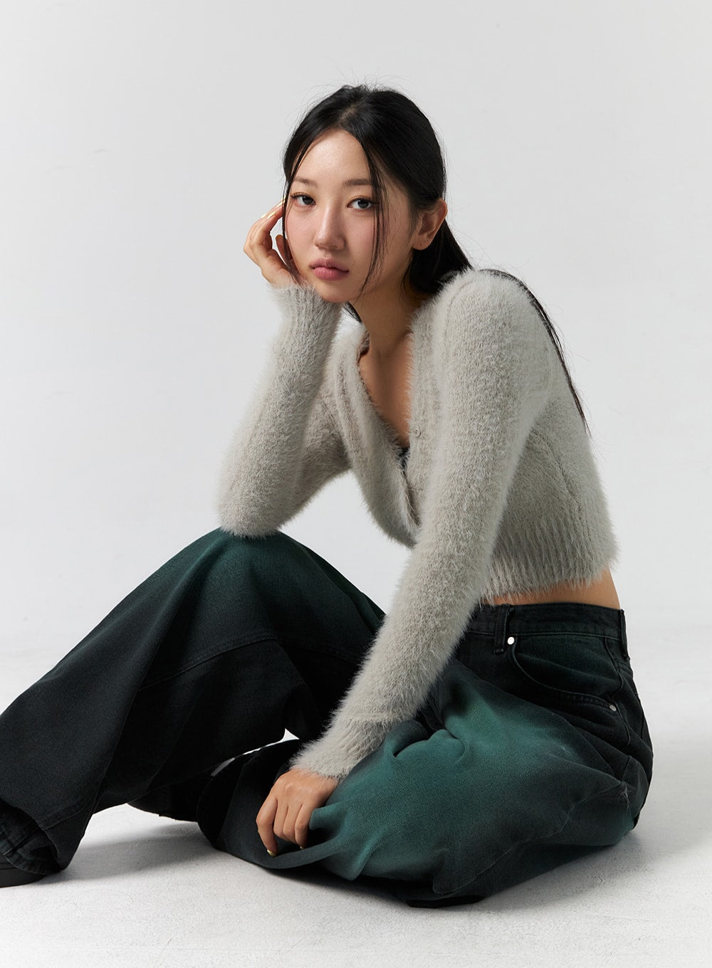 Comfy Wide Leg Color Jeans CS305 in dark green, seated editorial shot on model, relaxed wide-fit denim with green-black faded wash, layered with grey fluffy crop cardigan.