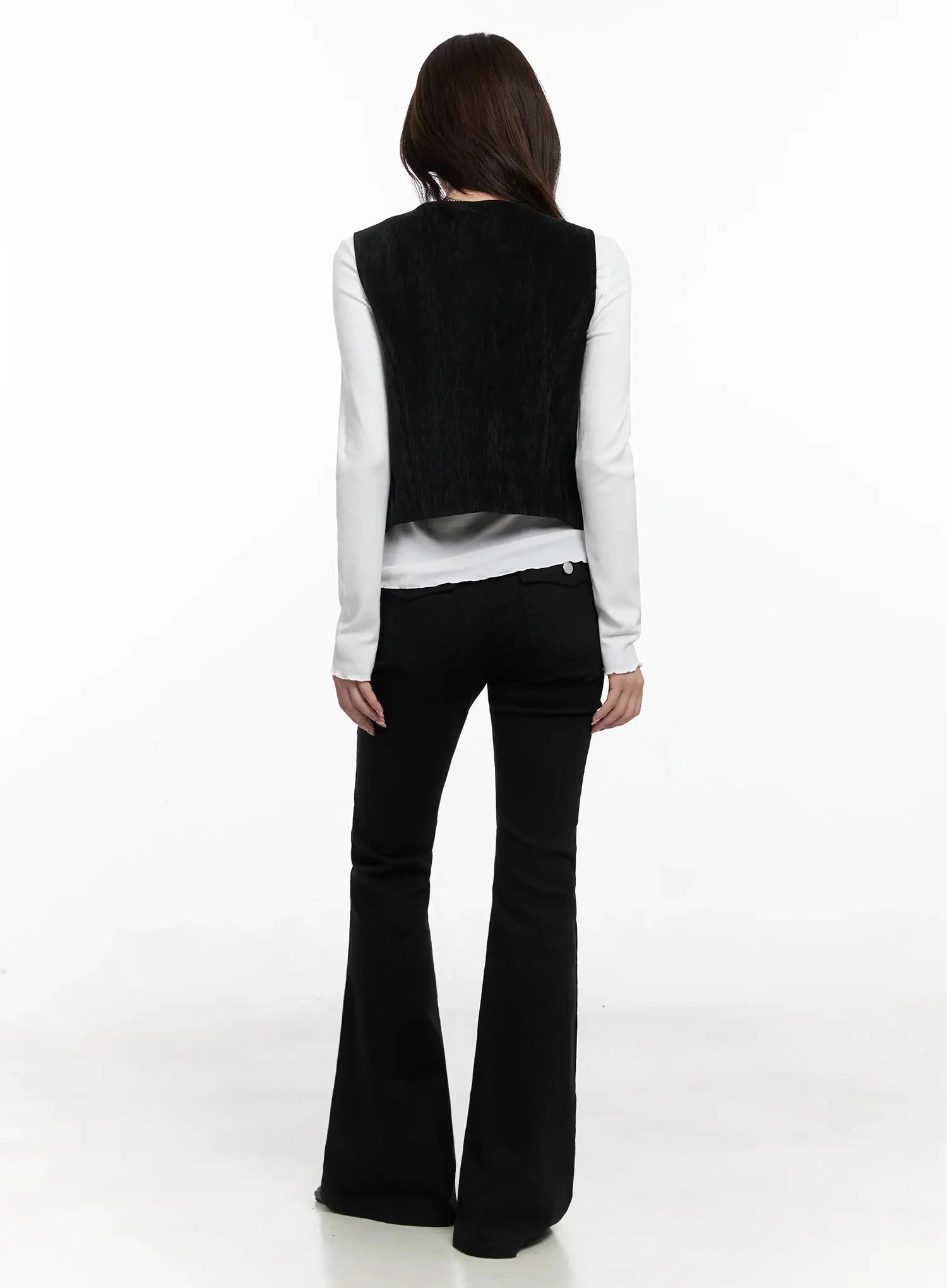 Dream Chic Black Flare Jeans IN514 in black, back full-length on model, rear view showing smooth fabric, flare hem drape, paired with black vest and white long-sleeve top.