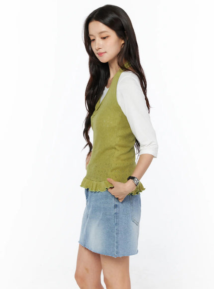 Frill Hem Halter Neck Top CU522 in green, side view on model with hand in pocket, openwork knit texture and ruffled hem detail shown, over white long-sleeve top and blue denim mini skirt.