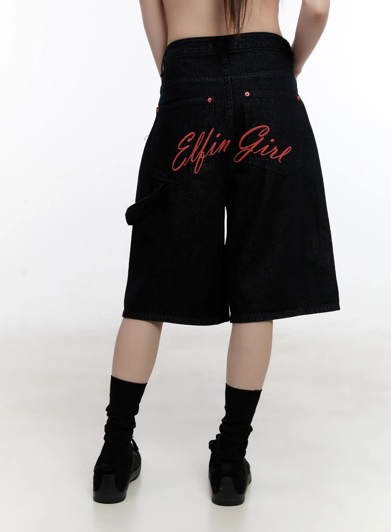 Red Text Graphic Embroidered Jorts CL504 in black, back view close-up on model, red 'Elfin Girl' script embroidery across back pockets, wide-leg hem and carpenter loop detail.