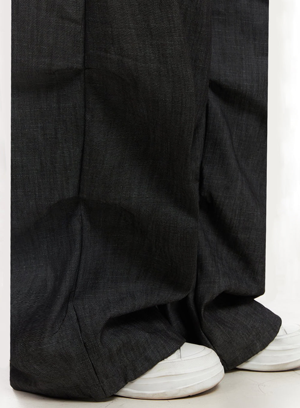 Pintuck Denim Sweatpants IY529 in black, close-up detail of lower leg and hem, showing wide-leg cotton denim drape and volume pooling over white sneakers.