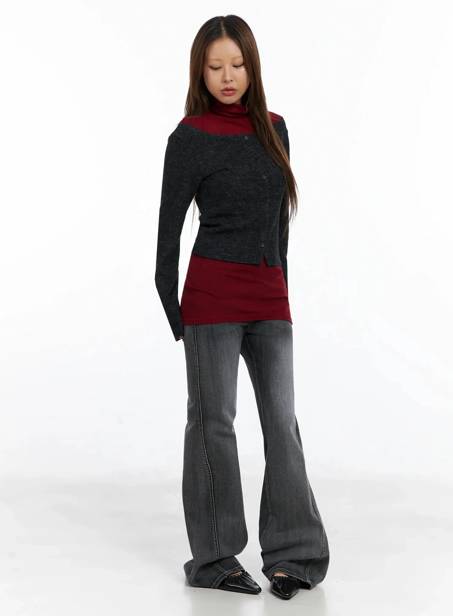 Phoe Flared Jeans ID503 in washed grey, full-length slight front-angle view on model looking down, styled with charcoal cardigan layered over burgundy turtleneck, wide flare hem visible.
