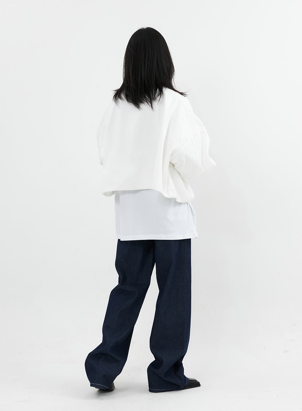 Stitched Jeans OO305 in Blue, back full-length on model, wide-leg dark indigo denim, contrast stitch visible along seams, paired with white jacket outfit.