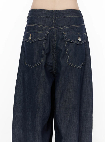 Rowen Baggy Jeans CU519 in dark blue, close-up back waist detail, showing two flap pockets with round metal snap buttons, contrast topstitching on waistband and pocket edges.
