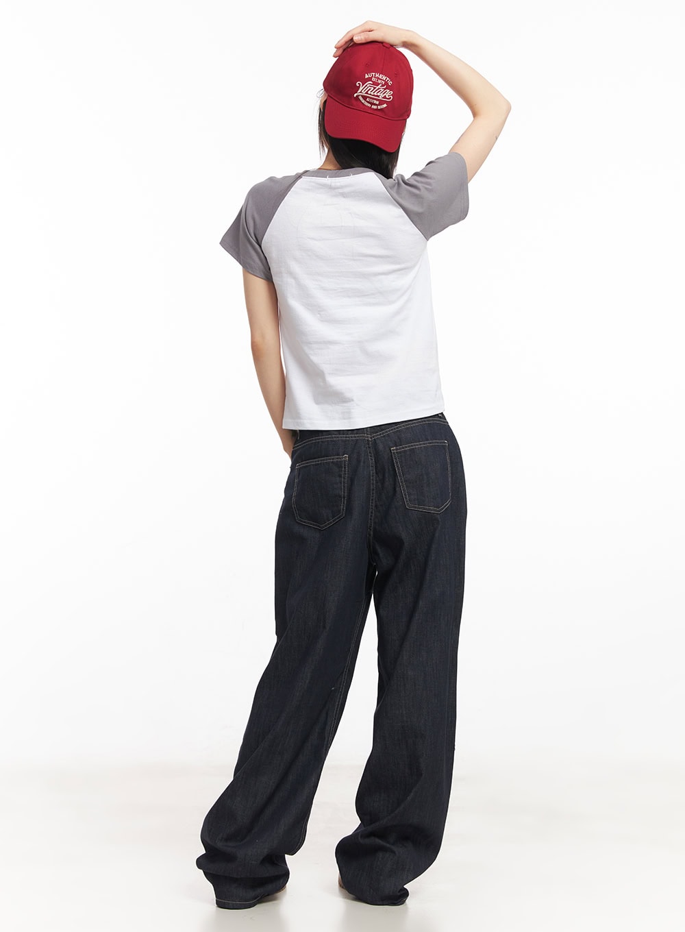 Ivara Wide-Leg Jeans CA522 in dark blue, back full-length view on model, oversized dual back pockets with contrast stitching, wide-leg silhouette, paired with raglan tee and red cap.