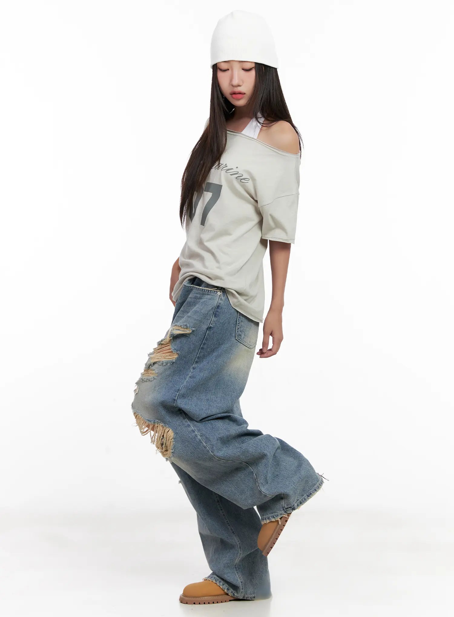 Manon Washed Distressed Wide Jeans CL518 in blue, three-quarter side editorial shot, model looking down mid-turn, wide-leg denim with large frayed rips catching movement.