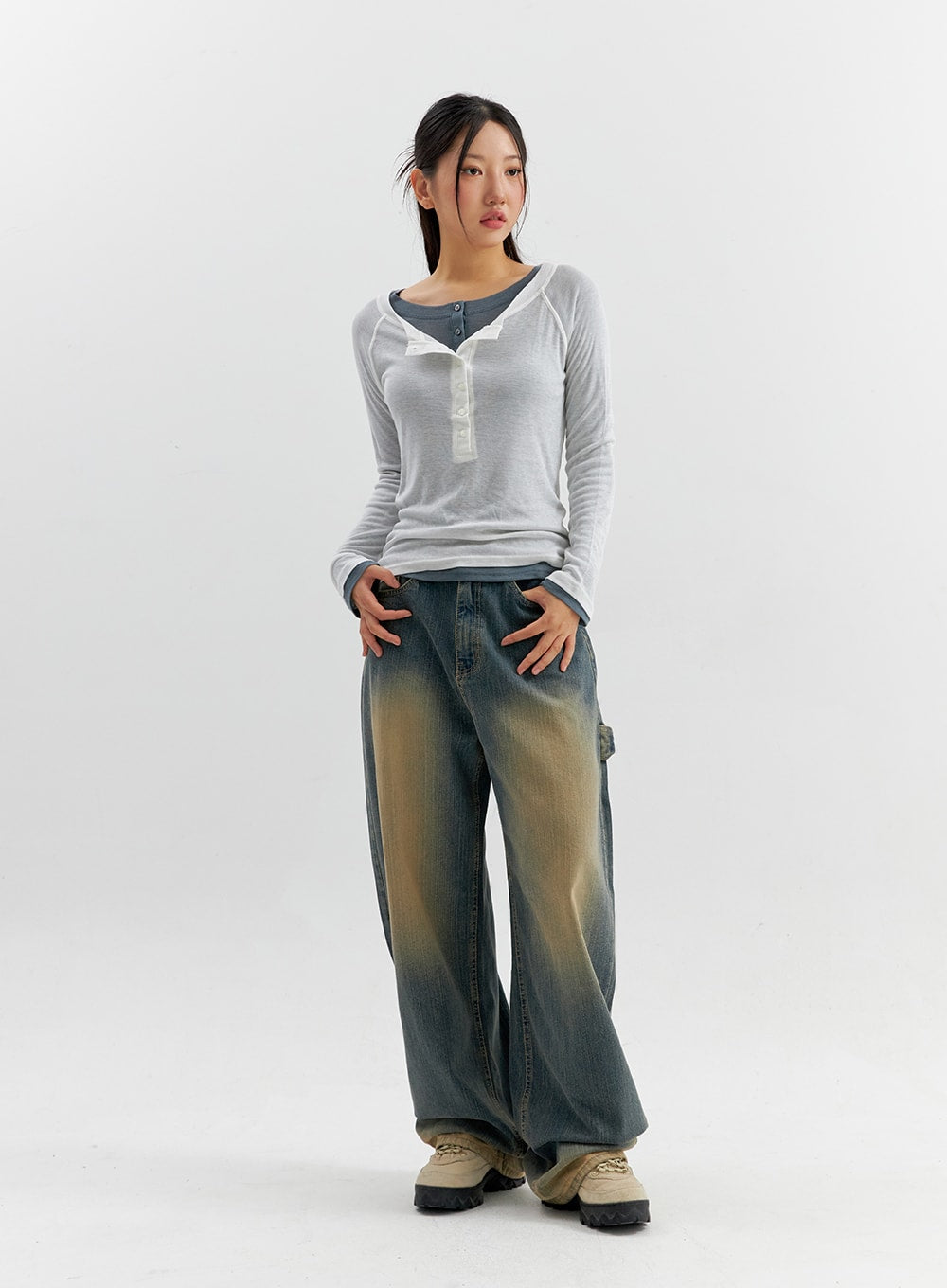 Vintage Wash Wide Leg Jeans CO306 in blue, full-body 3/4 front view on model, relaxed wide-fit cotton denim with vintage yellow fading, hands in pockets, styled with sheer layered top.
