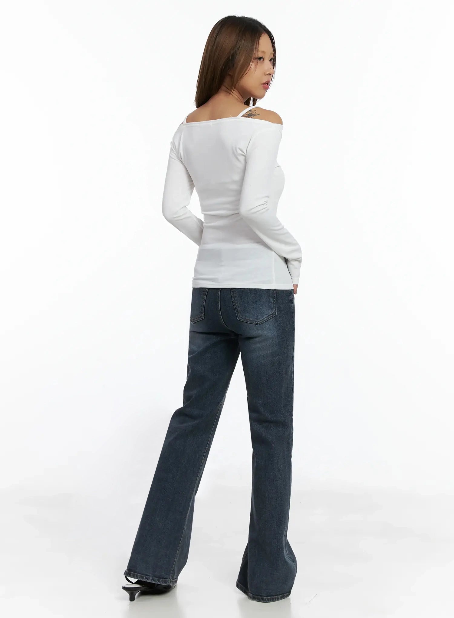 Rara Fleece Flared Jeans ID503 in blue, full back view on model, showing rear patch pockets and wide flared hem, paired with white off-shoulder top and black kitten-heel mules.