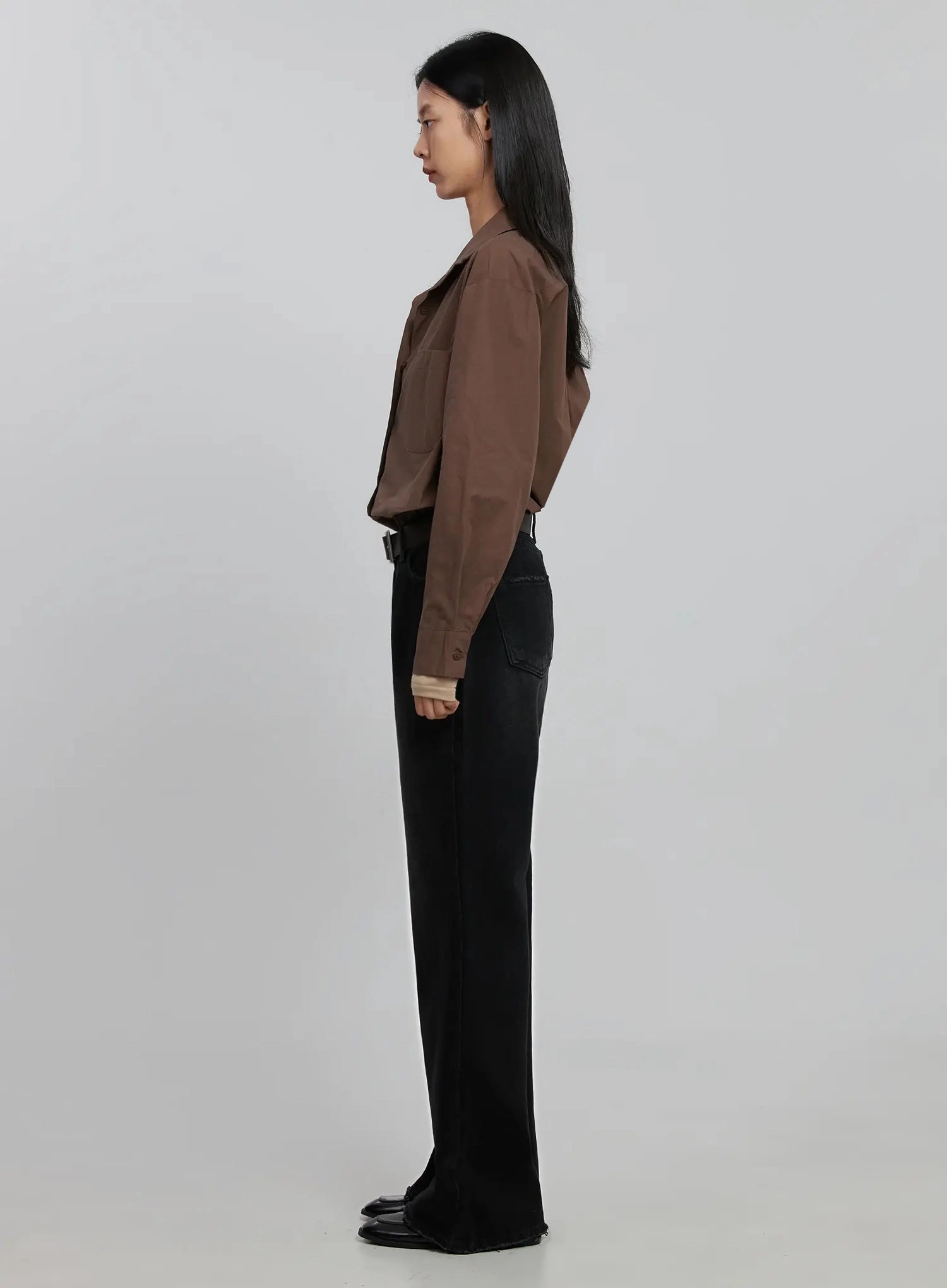 Imani Wide-Leg Flared Jeans ID516 in black, full side view on model, showing straight rise and gradual flare from knee to hem, brown shirt layered over beige top, long length, black loafers.