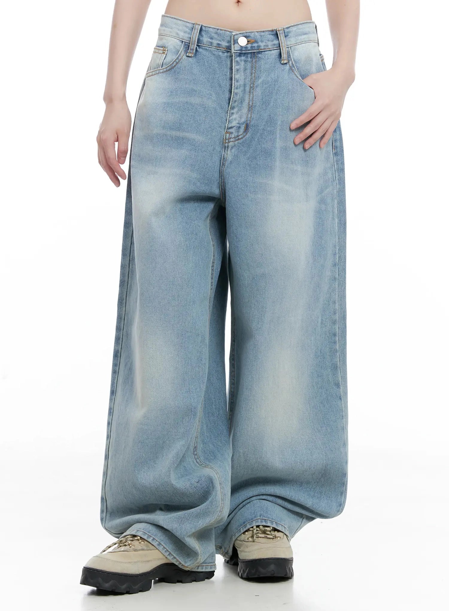 Dain Washed Wide-Leg Jeans IL531 in light blue, front mid-length shot on model with hand resting on hip, washed denim with wide-fit leg and draped hem over sneakers.