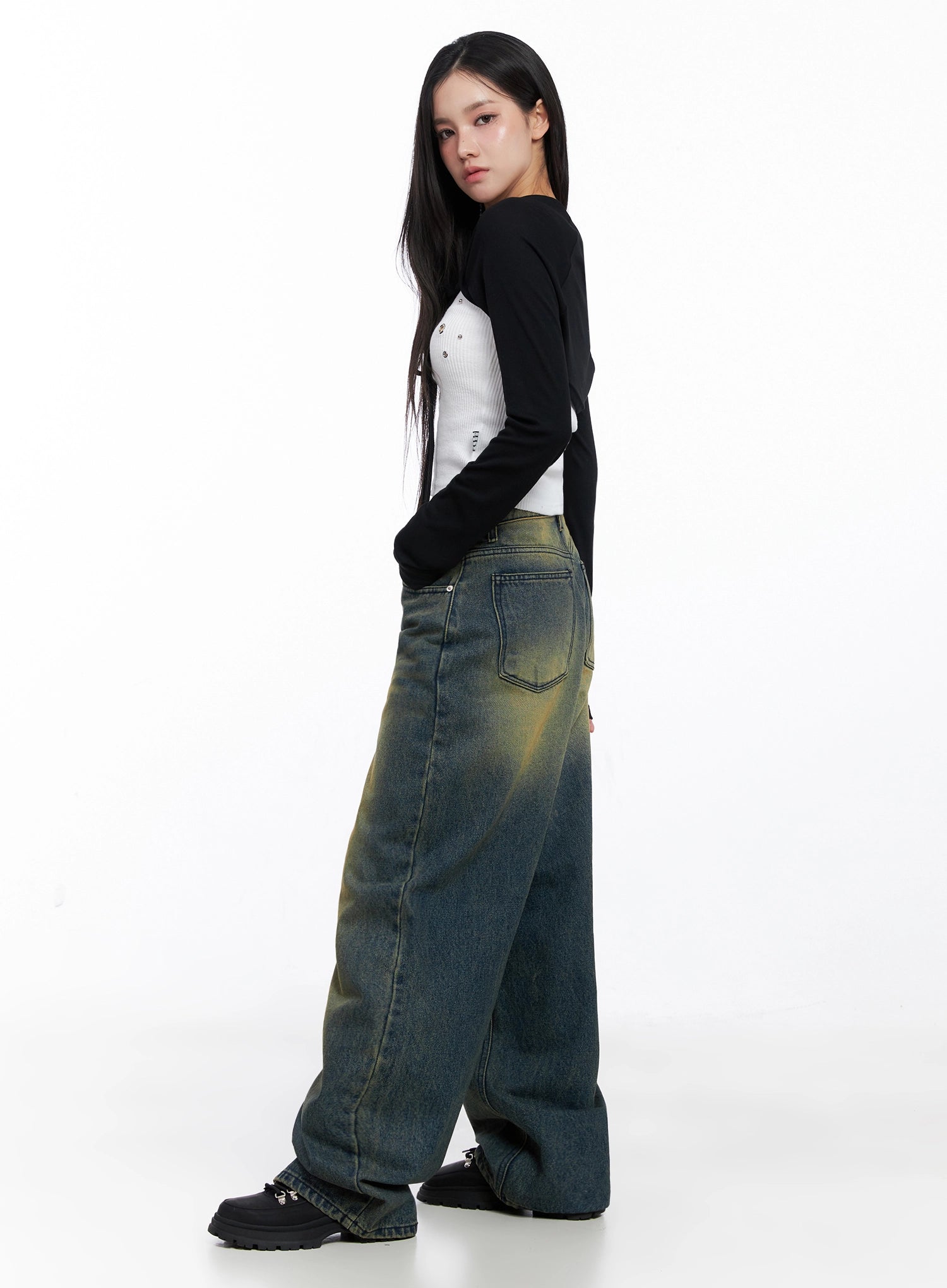 Elora Washed Baggy Jeans IS525 in dark blue, side-rear view on model, showing back pocket detail and yellow-green wash on wide baggy leg, paired with black and white crop top.